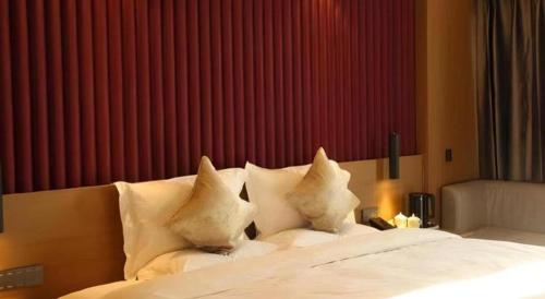 a bedroom with a bed with white pillows at Yanji Yanbian International Hotel in Yanji