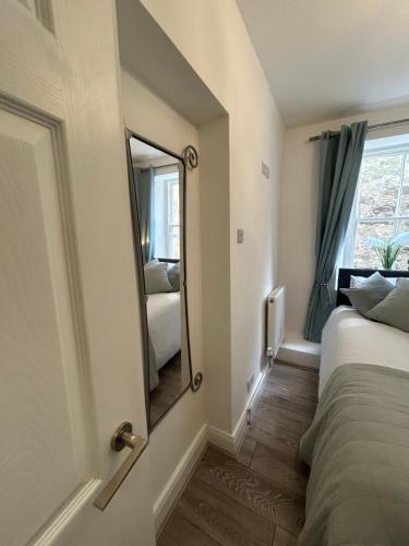 a bedroom with a mirror and a bed and a window at Corbridge Apartment in Corbridge
