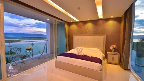 a bedroom with a bed and a balcony with a view at Phuglong Hotel in Phayao