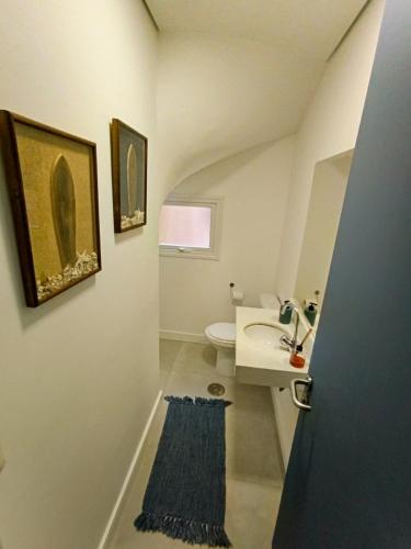 a white bathroom with a sink and a toilet at Casa com 3 suítes em condomínio com piscina em Juquehy in São Sebastião