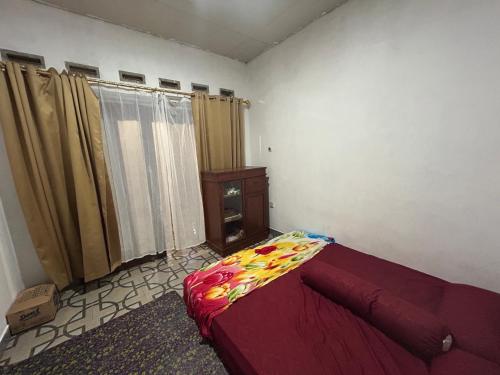 a bedroom with a bed and a window with curtains at Zian guest house in Seganteng