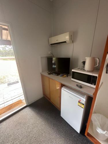 a small kitchen with a microwave and a refrigerator at Ravensthorpe Motel in Ravensthorpe