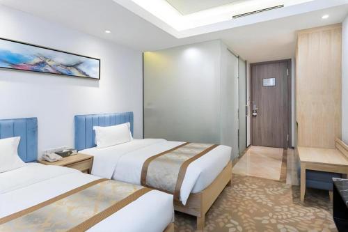 a hotel room with two beds and a bathroom at Golden Central Hotel Shenzhen in Shenzhen