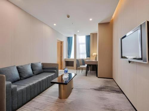 a living room with a couch and a flat screen tv at Golden Central Hotel Shenzhen in Shenzhen
