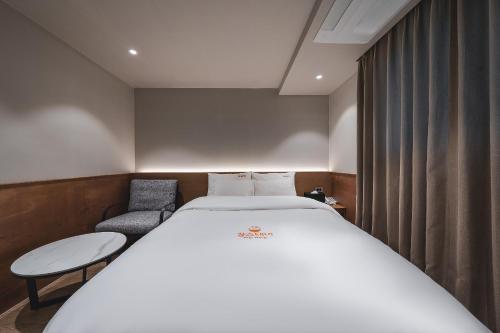 a bedroom with a large bed and a chair at Gridt Hotel & Home in Gyeongju
