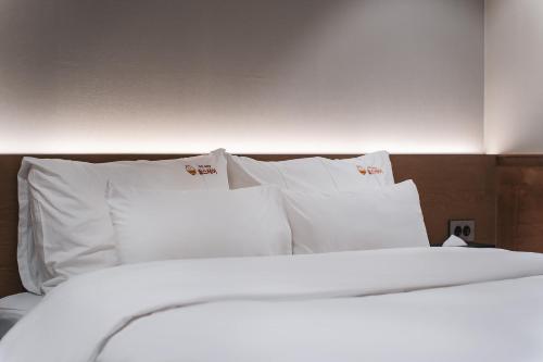 a white bed with white pillows in a room at Gridt Hotel & Home in Gyeongju