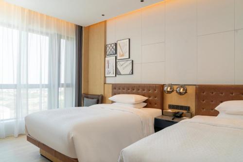 a bedroom with two beds and a window at Four Points by Sheraton Shanghai International Tourism and Resorts Zone in Nanhui