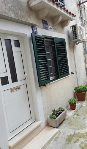 a white house with green shutters and a door at Antea in Split