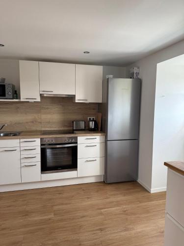 a kitchen with white cabinets and a stainless steel refrigerator at Villa19hundert5 moderne Ferienwohnungen in zentraler Lage in Lindenberg im Allgäu