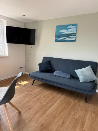 a living room with a blue couch and a flat screen tv at Villa19hundert5 moderne Ferienwohnungen in zentraler Lage in Lindenberg im Allgäu