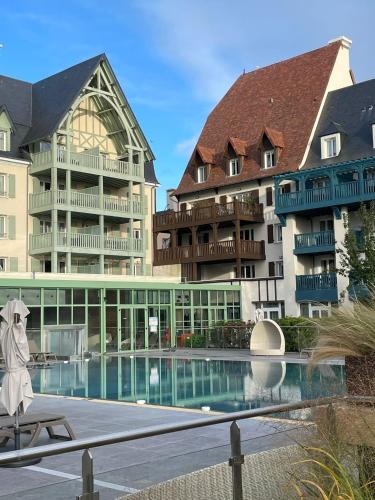 un hôtel avec une piscine en face de certains bâtiments dans l'établissement Presqu île de la touques deauville N 3404, à Deauville