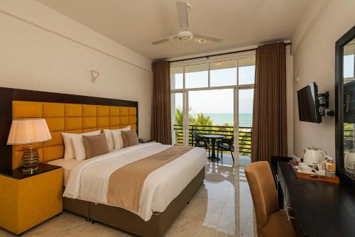 a bedroom with a bed and a television and a balcony at Beverly Beach Hotel & Transit in Negombo