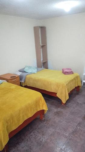 two beds in a room with yellow sheets at Departamento C-3 in Mexico City