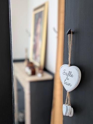 a white heart hanging on a black door at La Maison d'Arlette - Maison d'Hôte et Gite au coeur de l'Isère à 10 mn de Voiron, capitale de la Chartreuse, et du Lac de Paladru in Saint-Blaise-du-Buis