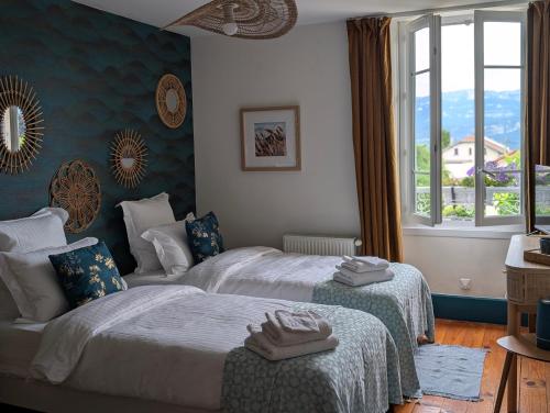 a hotel room with two beds and a window at La Maison d'Arlette - Maison d'Hôte et Gite au coeur de l'Isère à 10 mn de Voiron, capitale de la Chartreuse, et du Lac de Paladru in Saint-Blaise-du-Buis