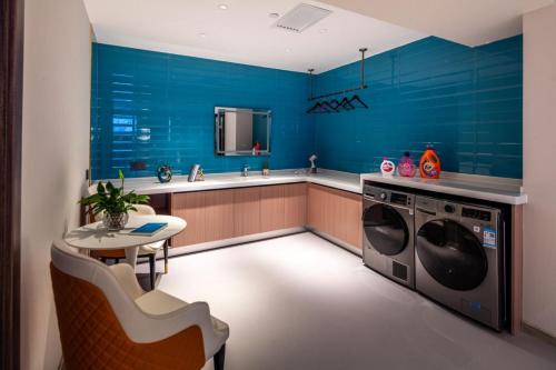 a blue kitchen with a table and a washing machine at 忻州古城万信至格酒店 in Xinzhou Zhan