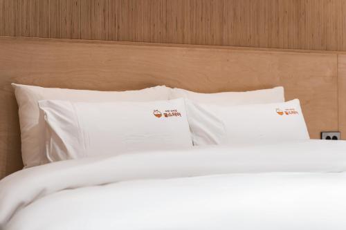 a bed with white sheets and pillows at Gridt Hotel & Home in Gyeongju