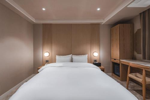 a bedroom with a large white bed and two lights at Gridt Hotel & Home in Gyeongju