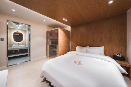 a bedroom with a large white bed and a bathroom at Gridt Hotel & Home in Gyeongju
