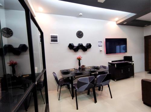 a dining room with a table and chairs and a television at SNOW Apartment - Near Clark International Airport and Dinosaurs Island in Mabalacat