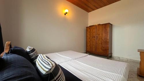 a bedroom with a bed and a wooden cabinet at RIVINSON Villa Beruwala in Beruwala