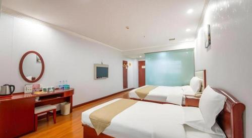 a bedroom with two beds and a desk and a mirror at GreenTree Inn Yinchuan Pedestrian Street East Liqun Street Express Hotel in Yinchuan