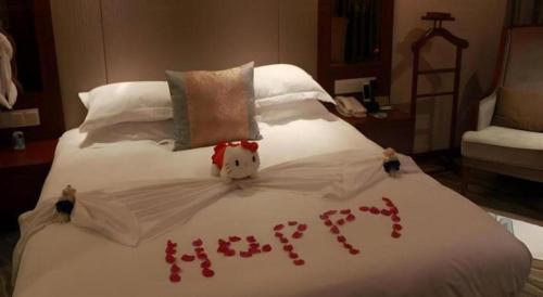a bed with red rose petals written on it at Xiamen Airlines Quanzhou Hotel in Quanzhou
