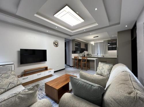 a living room with a couch and a tv at Great Homes in Kira