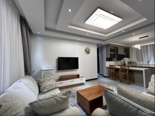 a living room with a couch and a tv at Great Homes in Kira