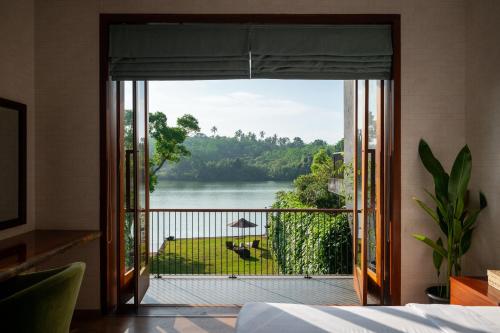 a bedroom with a view of a river from a balcony at Kurokawa Kalutara in Kalutara