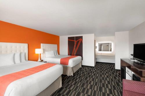 a hotel room with two beds and a flat screen tv at Howard Johnson by Wyndham Modesto Ceres in Ceres