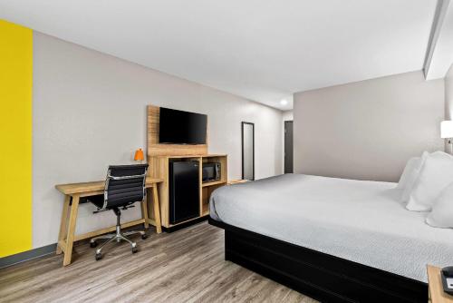 a hotel room with a bed and a desk with a computer at Super 8 by Wyndham Lewiston Auburn Area in Lewiston