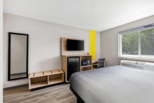 a hotel room with a bed and a television at Super 8 by Wyndham Lewiston Auburn Area in Lewiston