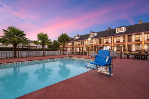 a pool with a blue chair in front of a building at Baymont by Wyndham Commerce GA Near Tanger Outlets Mall in Commerce