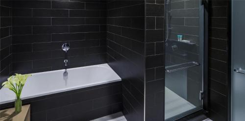 a black tiled bathroom with a tub and a glass shower at Hyatt Centric Times Square New York in New York
