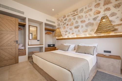 a bedroom with a large bed and a stone wall at Analeia Luxury Hotel - Adults Only in Kalymnos