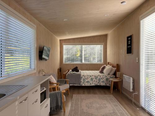 a room with a bed and a kitchen with a bed at Cotman Cottage on Coatesville in Kumeu