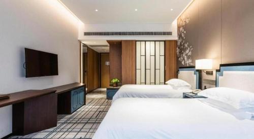 a hotel room with two beds and a flat screen tv at International Conference Hotel Nanjing in Nanjing