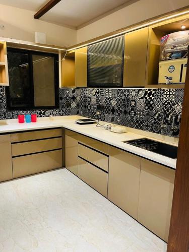 a kitchen with yellow and white cabinets and black and white tiles at The Divine Villa! in Indore