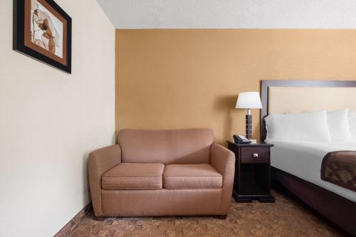 a hotel room with a chair and a bed at Village Inn Clemmons-Winston Salem, Trademark by Wyndham in Clemmons
