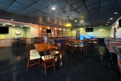 a restaurant with wooden tables and chairs and a bar at Village Inn Clemmons-Winston Salem, Trademark by Wyndham in Clemmons