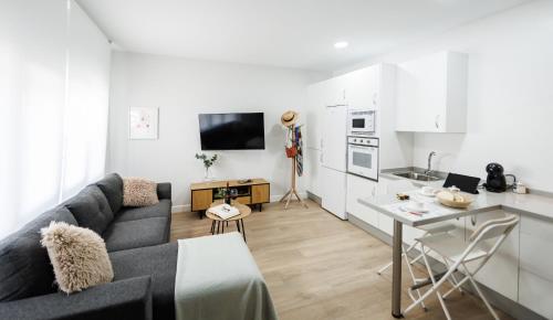 a living room with a gray couch and a kitchen at Apartamentos LUXURY SUITES MACABEO in Almendralejo
