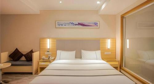 a bedroom with a large white bed and a couch at City Comfort Inn Nanning Guangxi University in Nanning