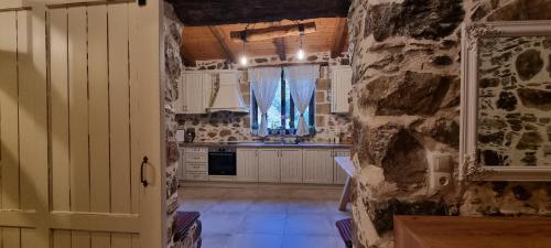 cocina con armarios blancos y pared de piedra en Mesavlia Traditional Stone House, en Mesávlia