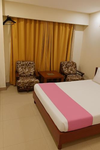 a hotel room with a bed and two chairs at Hotel Kundan Stay in Vijayawāda