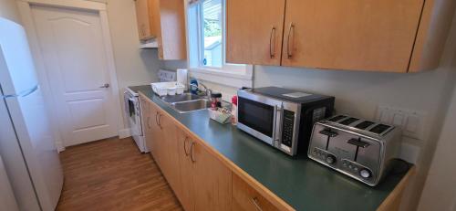 a kitchen with a counter with a microwave and a sink at Guest Suite in Langford Victoria in Victoria