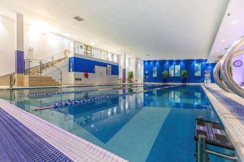 a large indoor swimming pool with blue water at The Lodge At Meyrick Park in Bournemouth