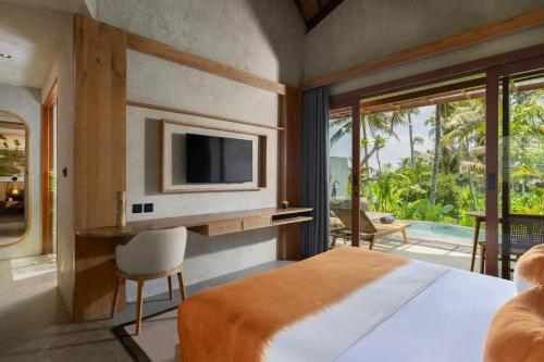 a bedroom with a bed and a tv on the wall at Inara Alas Harum in Ubud