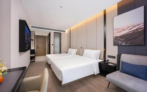 a hotel room with two beds and a couch at 威海市区威高广场万信至格酒店 in Weihai