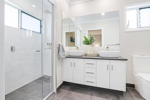 a bathroom with two sinks and a shower at Whitewash House in Bargara